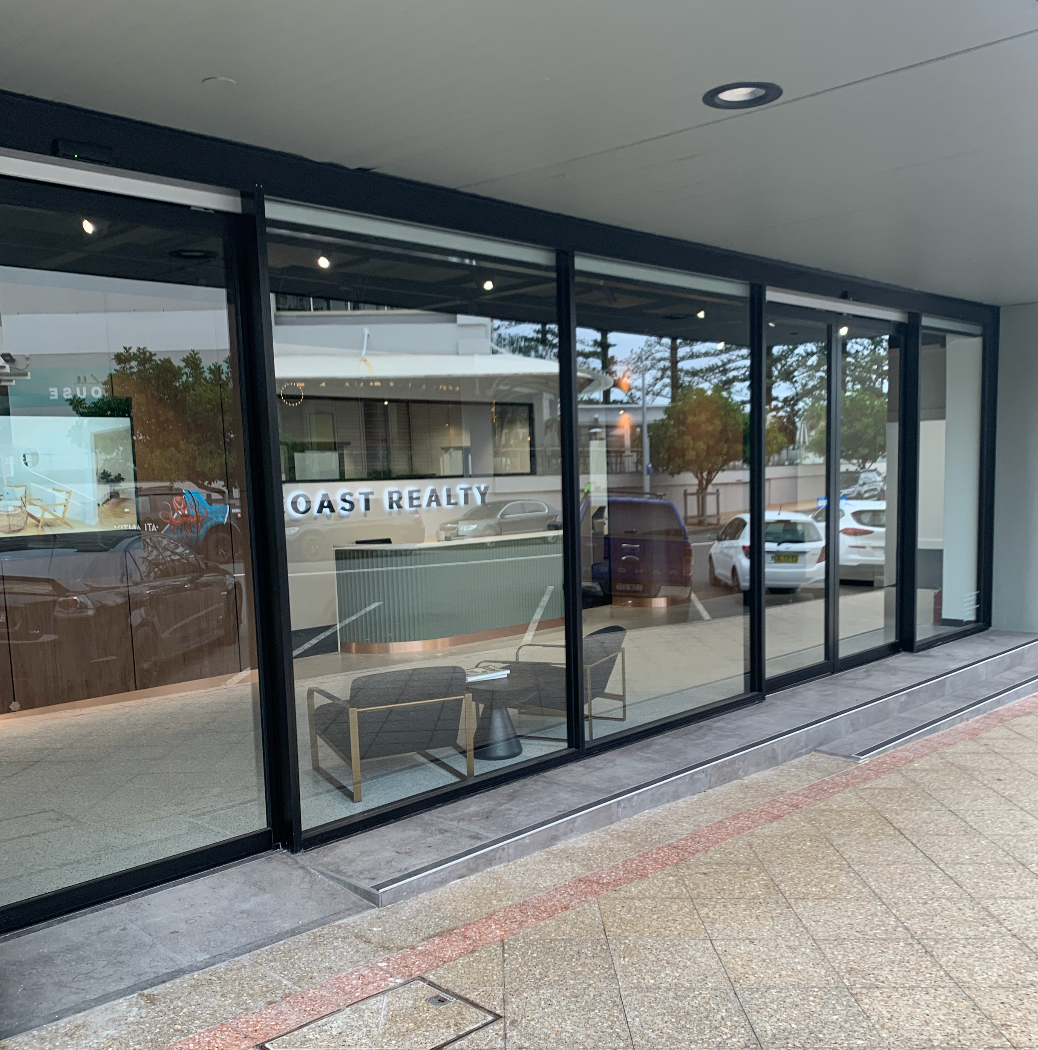 A Building with A Lot of Windows and A Lot of Cars Parked — Reflect Glass In Tuggerah, NSW