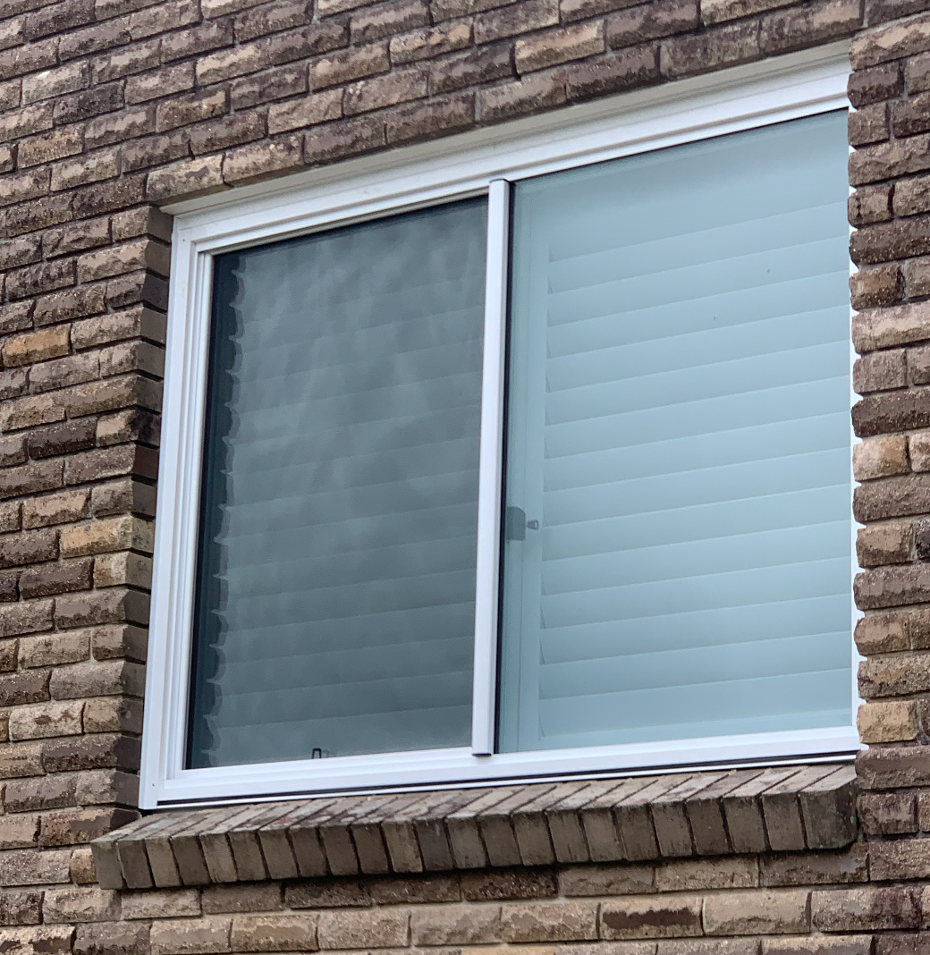A Window on The Side of A Brick Building with Blinds on It — Reflect Glass In Tuggerah, NSW