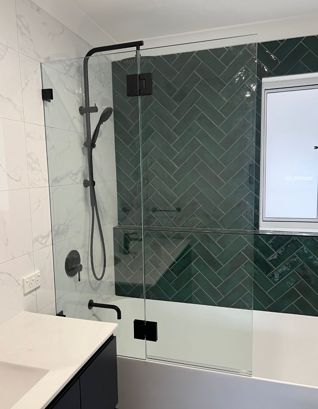 A Bathroom with Green Tiles and A Glass Shower Door — Reflect Glass In Tuggerah, NSW