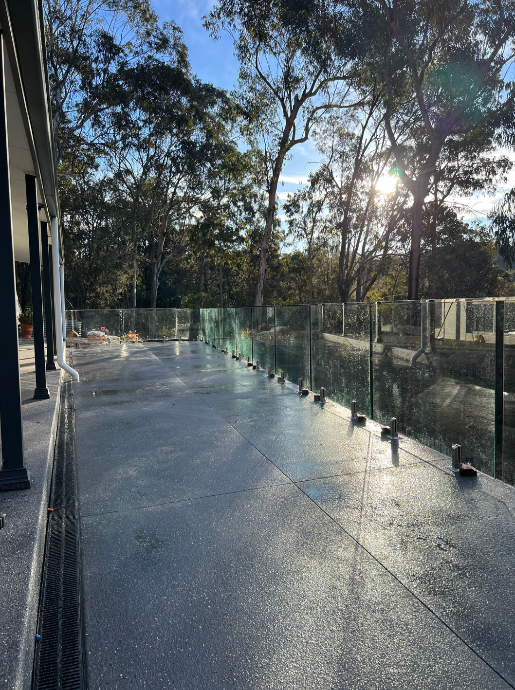 A Concrete Walkway with A Glass Railing and Trees — Reflect Glass In Tuggerah, NSW