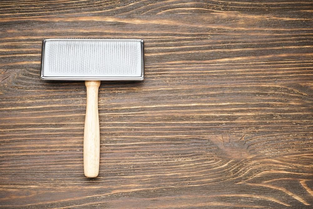 A Brush With a Wooden Handle is Sitting on a Wooden Table — Fluffy Paws Pet Grooming In Wingham, NSW