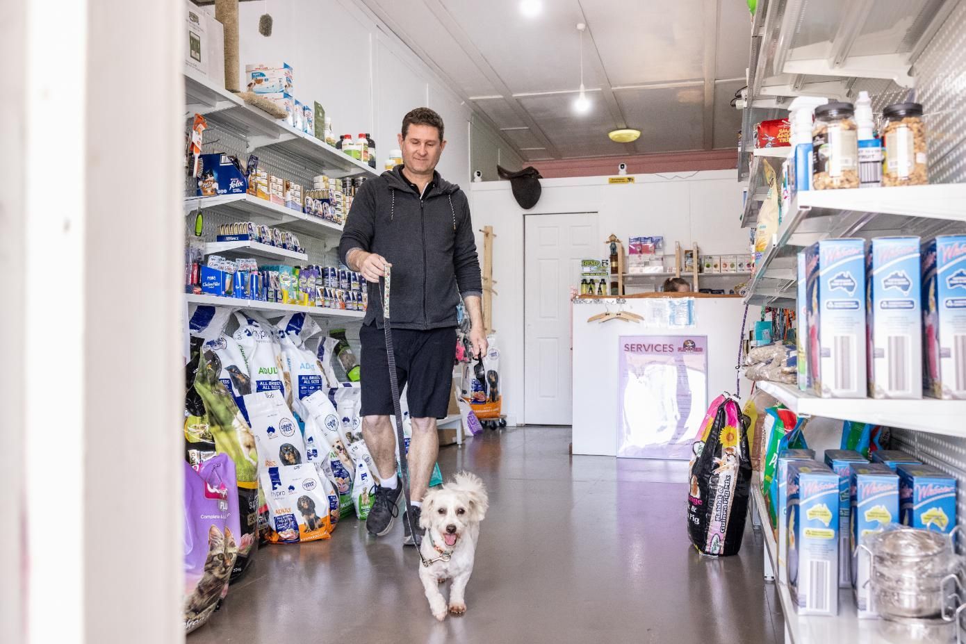A Man is Walking a Dog in a Pet Store — Fluffy Paws Pet Grooming In Wingham, NSW