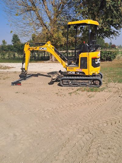 Un miniescavatore JCB giallo parcheggiato su un terreno sterrato in un ambiente rurale.