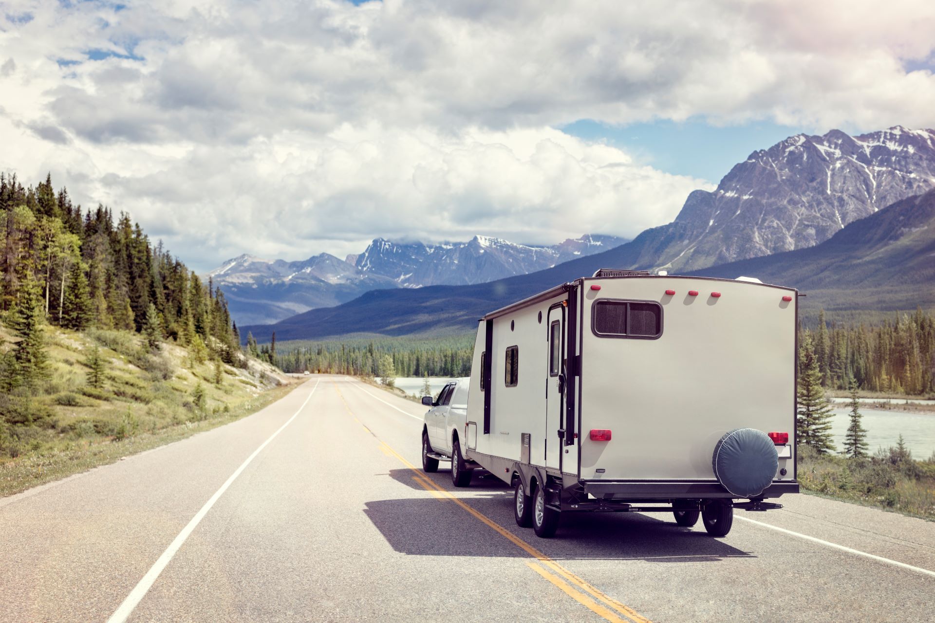 A truck is towing a trailer down a mountain road.