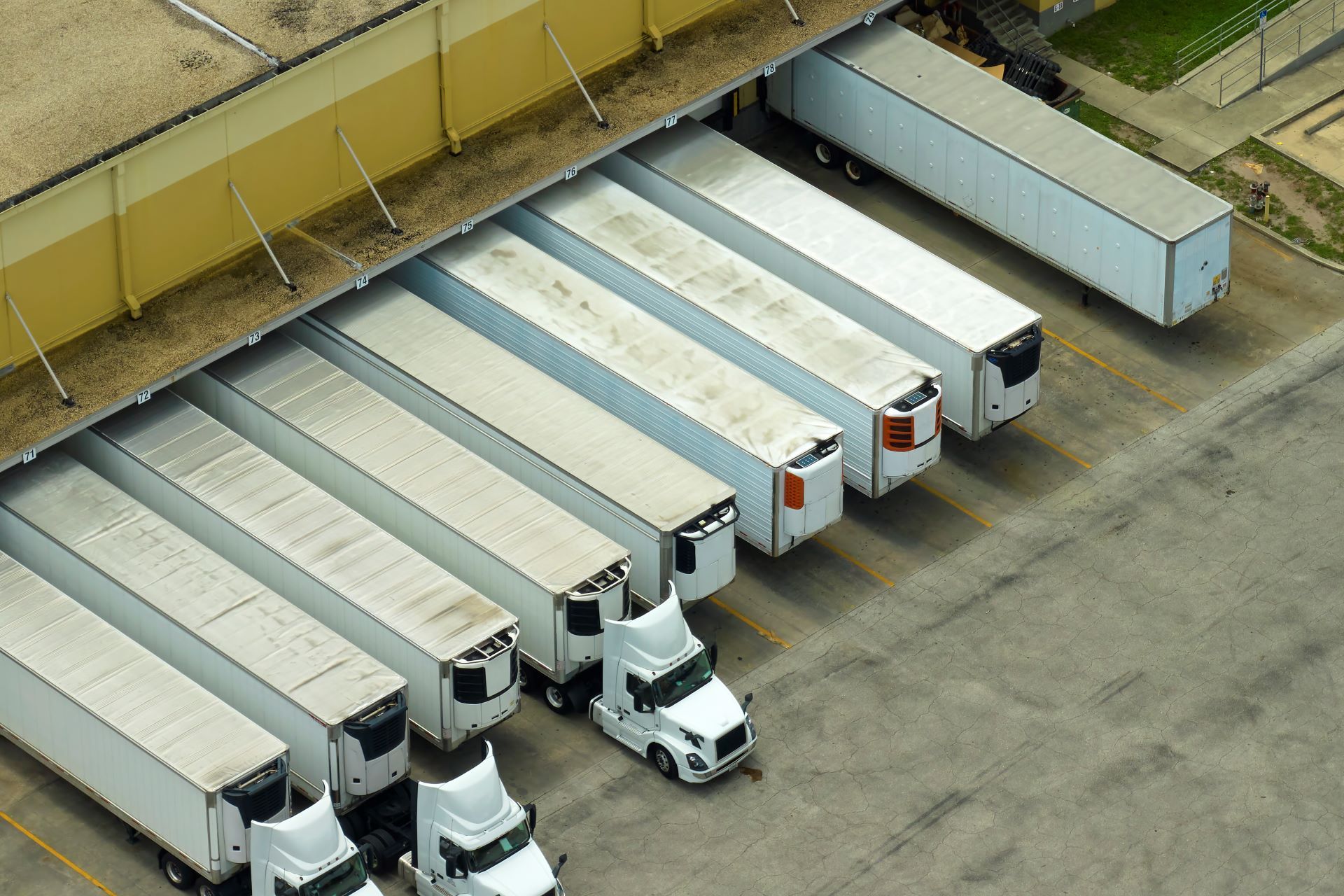 A row of semi trucks are parked under a building