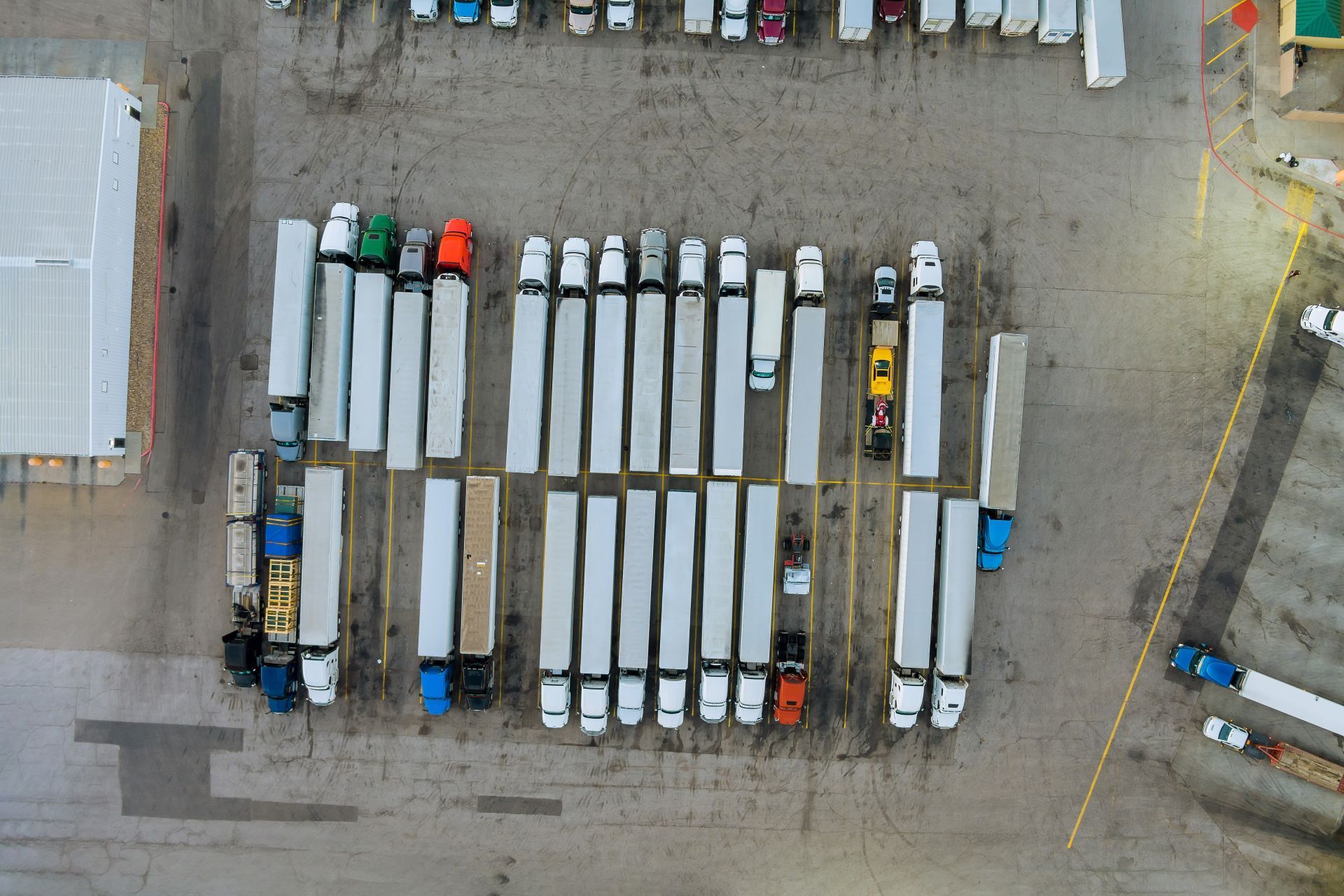 Overhead view of a parking lot filled with semi-trucks and trailers in a logistical setting.