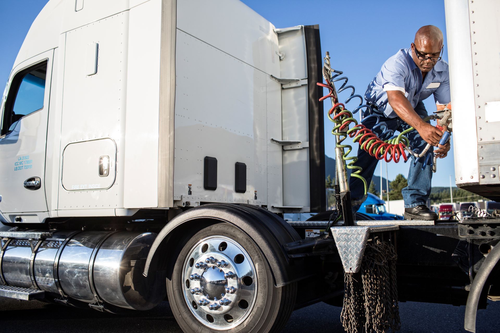 A man is working on the side of a semi truck.