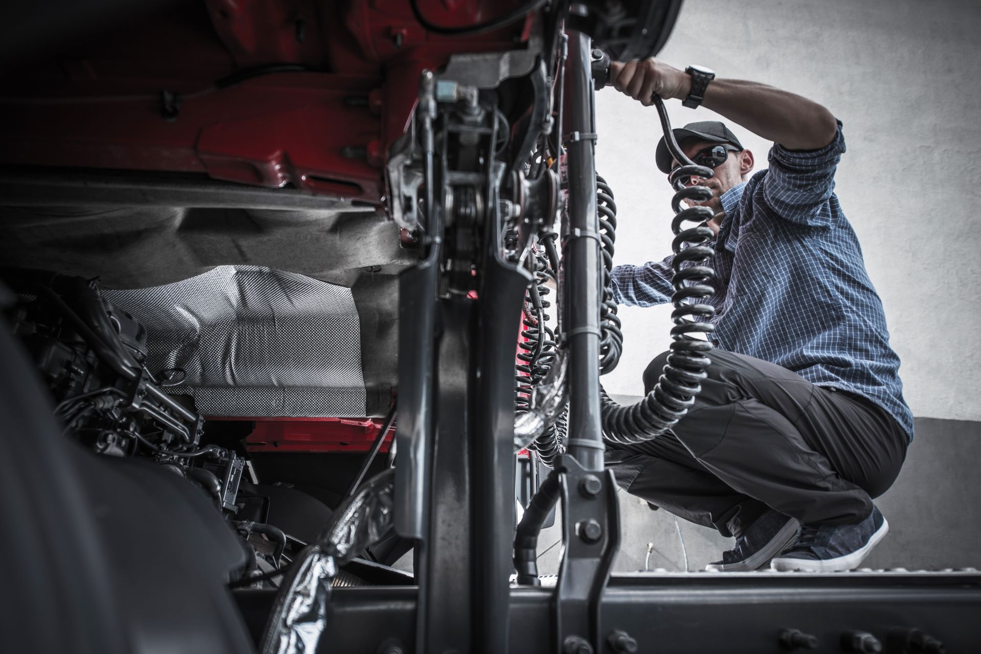 A man is working on the underside of a truck.