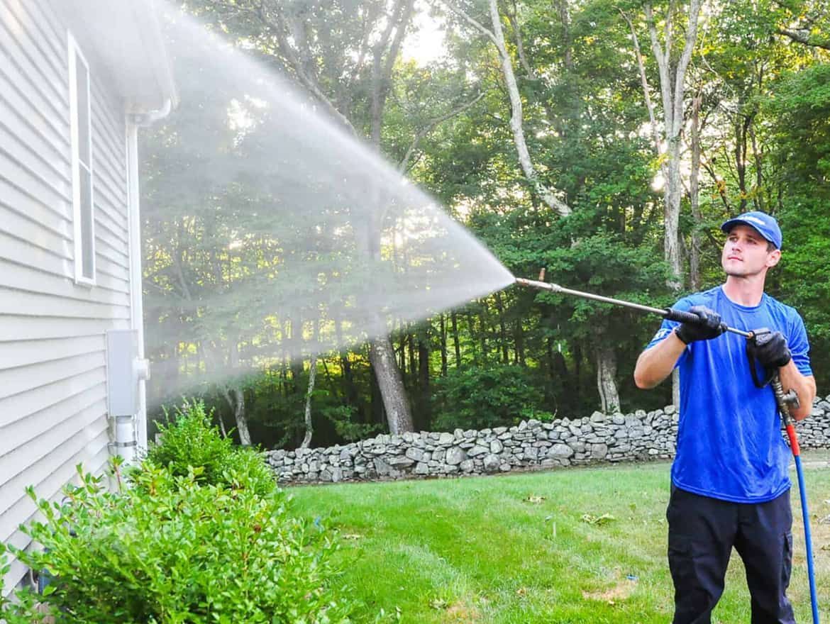 Pressure washing the side of this home at a safe distance not to damage the surface.