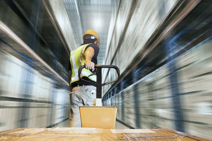 Worker in a safety vest and helmet moving a cart Worker in a safety vest and helmet moving a cart