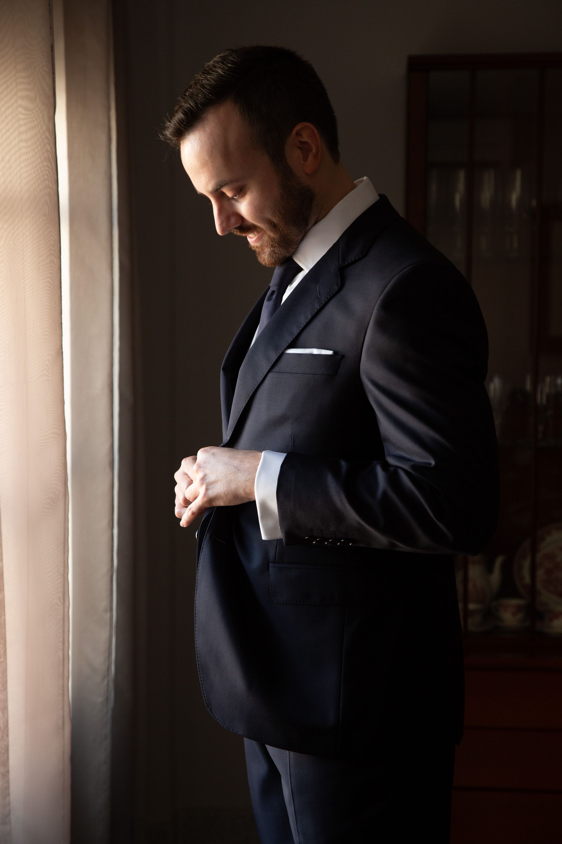 Fotógrafo de bodas en Valencia capturando al novio abrochándose la chaqueta el día de su casamiento.