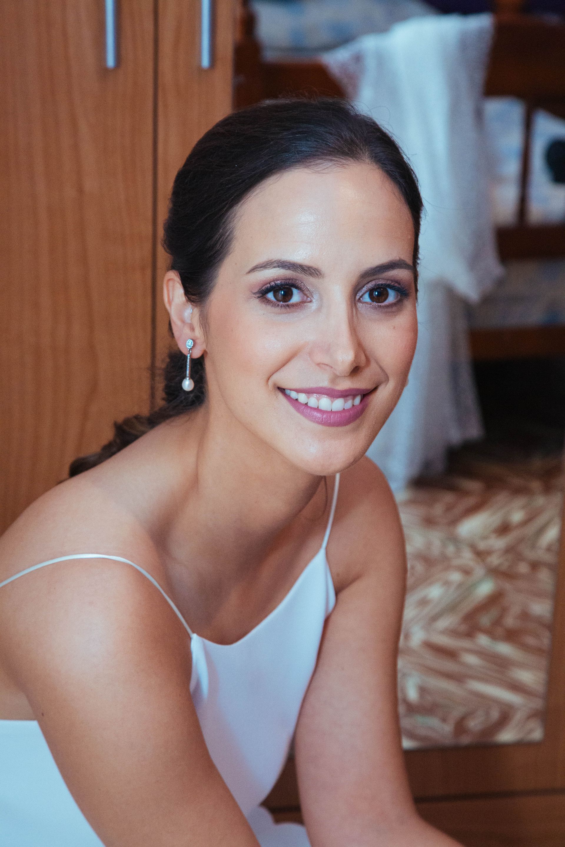 Fotógrafo de bodas en Valencia capturando a la madre de la novia ayudando a su hija a abrochar su vestido el día de su enlace.