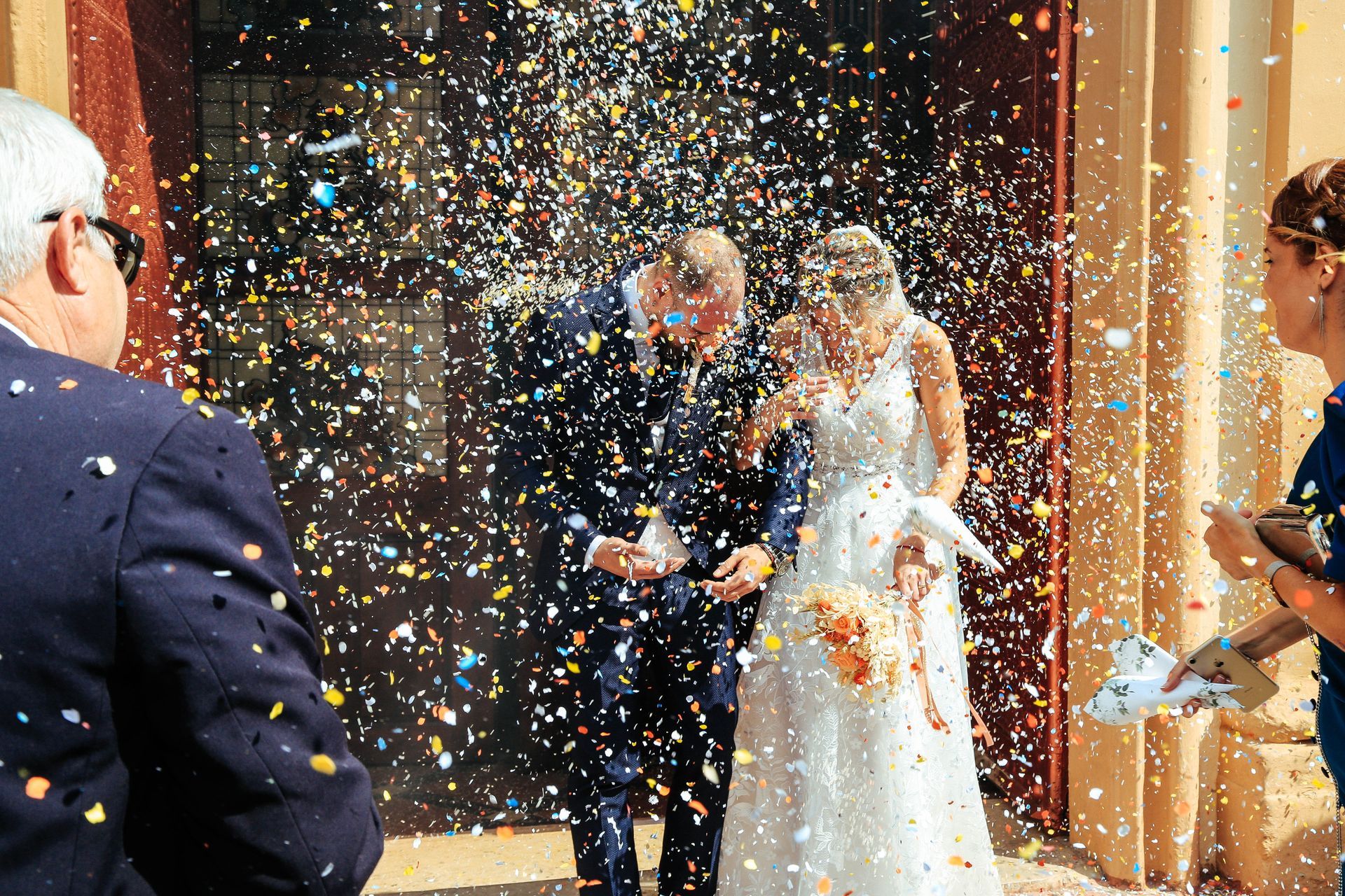Fotógrafo de bodas capturando la salida novios de la iglesia el día de su boda en Valencia, España.