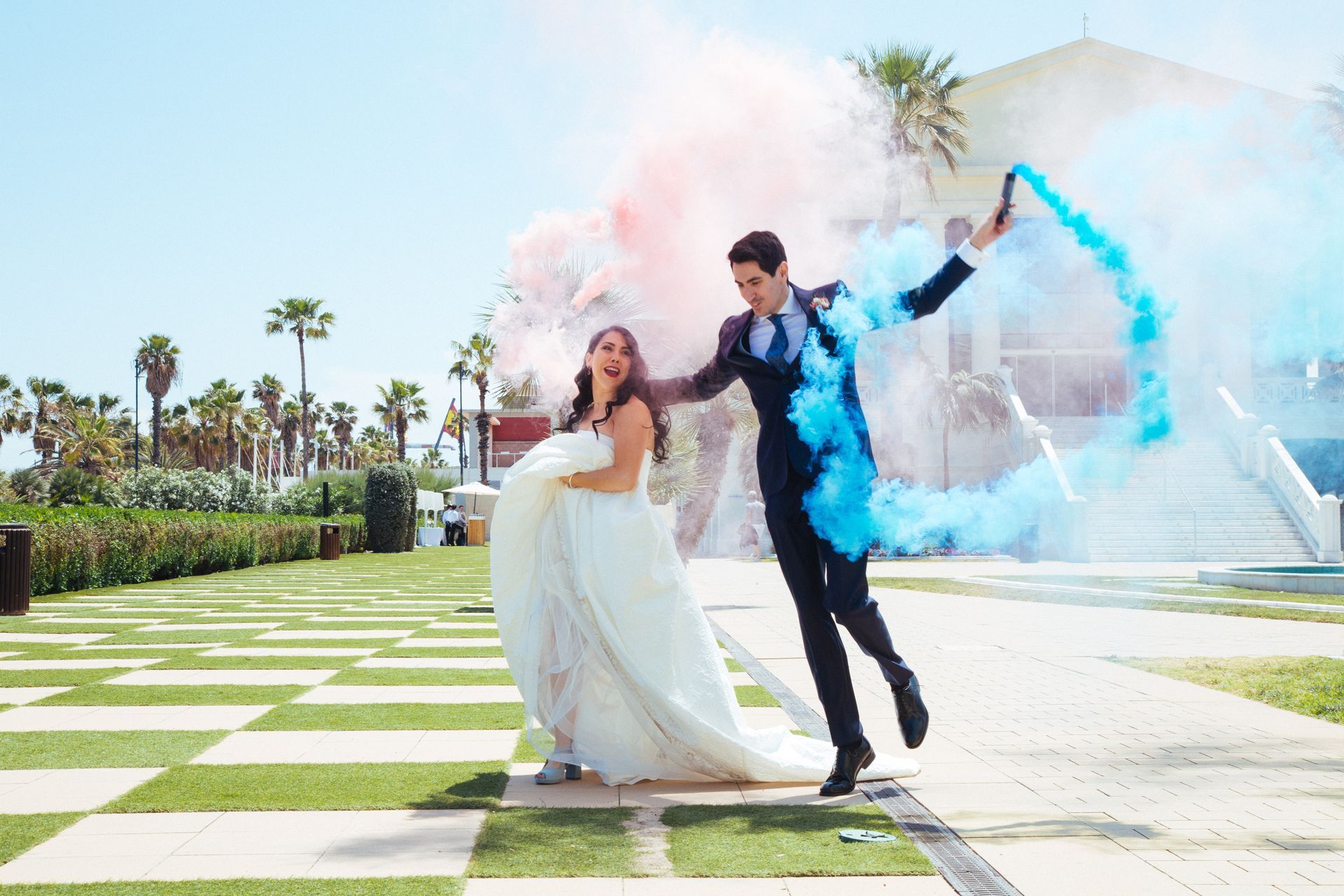Foto de los recién casados, con bengalas de humo, entrando al cóctel de su boda, listos para celebrar con sus seres queridos