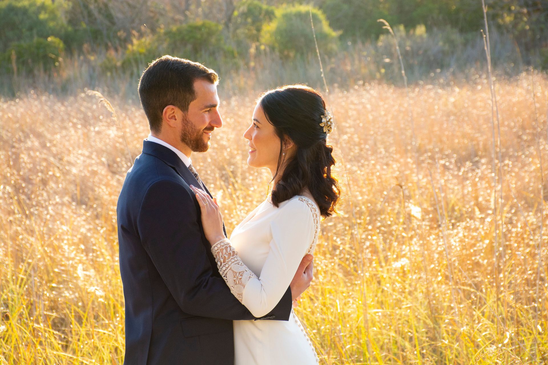 Fotógrafo de bodas capturando a pareja de novios ,con sus trajes de boda, mirándose románticamente en el campo en Valencia, España.