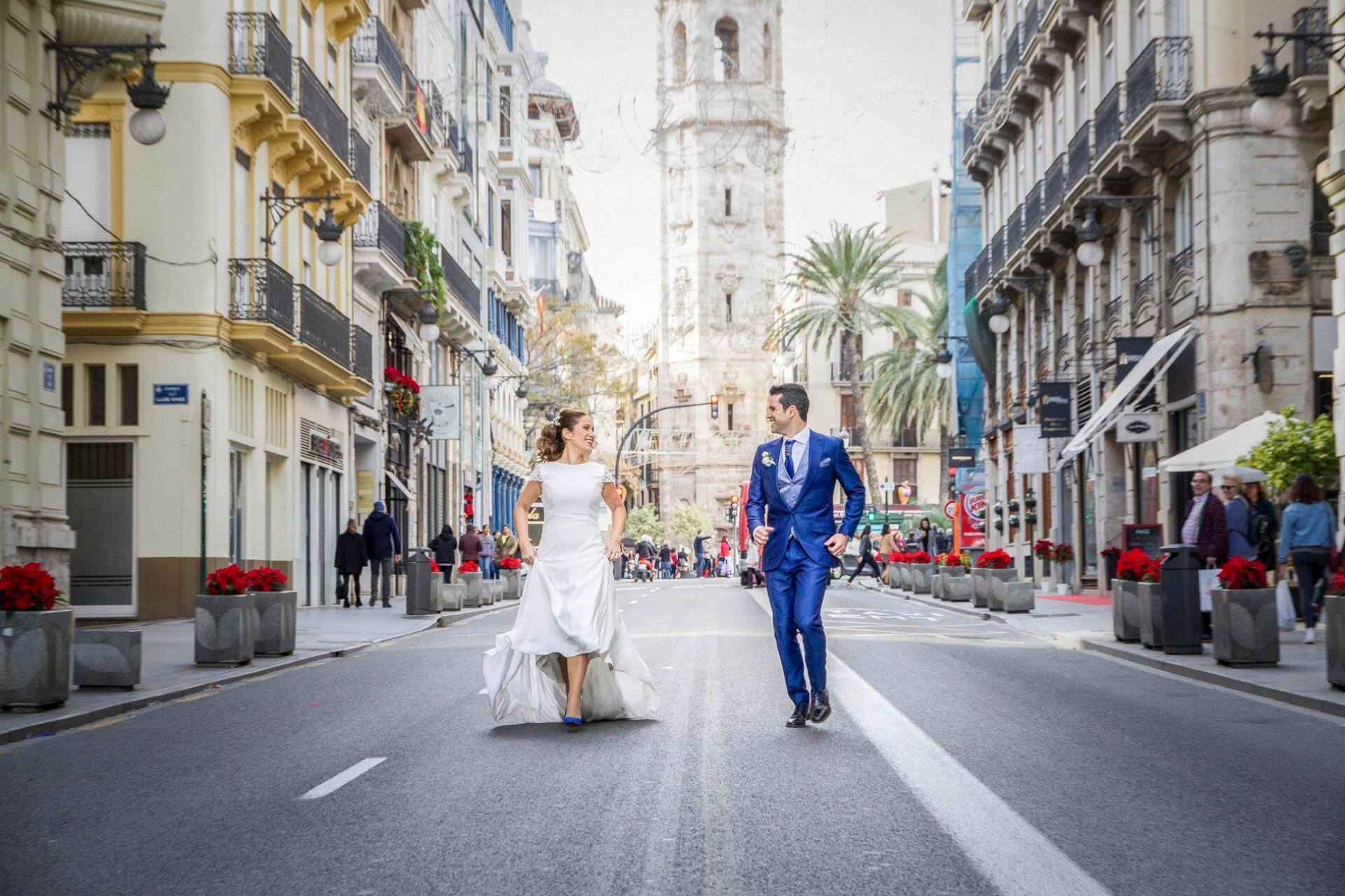 Fotógrafo de bodas capturando a una pareja de recién casados corriendo por la calle La Paz de Valencia, España.