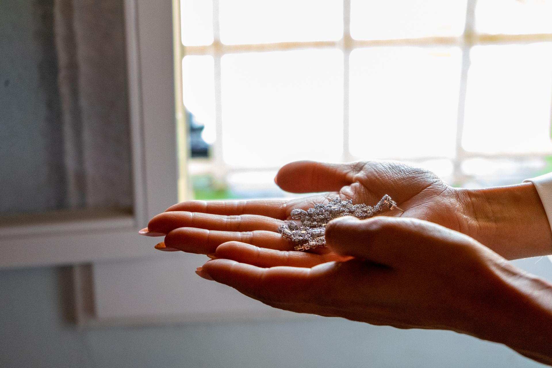 Fotógrafo de bodas en Valencia capturando como la novia sostiene en sus manos los pendientes de plata que llevará en su enlace.