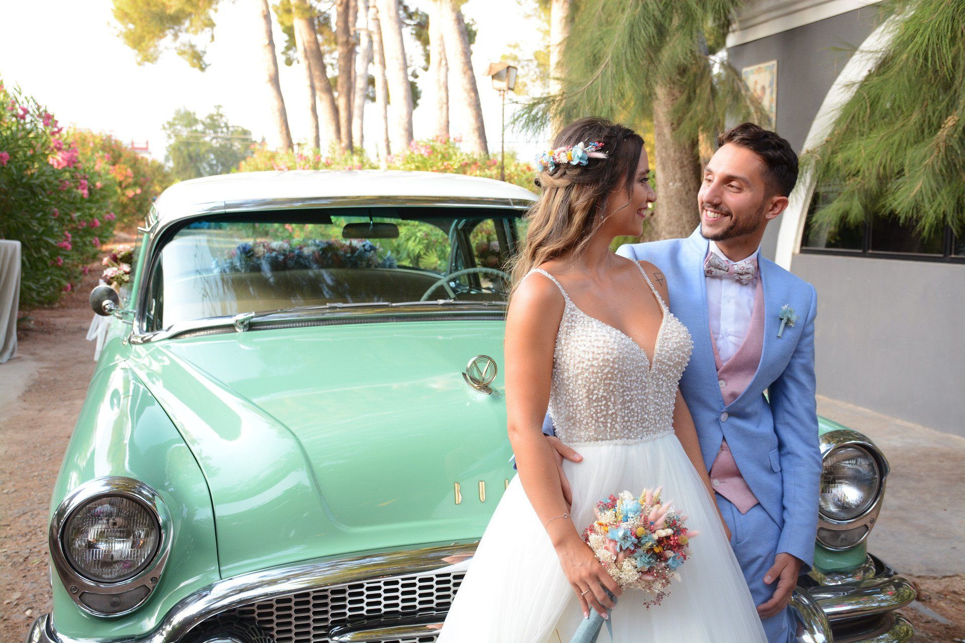 Novios enamorados mirándose con ternura junto al coche nupcial, en un gesto de amor y conexión en el día más importante de sus vidas en su boda