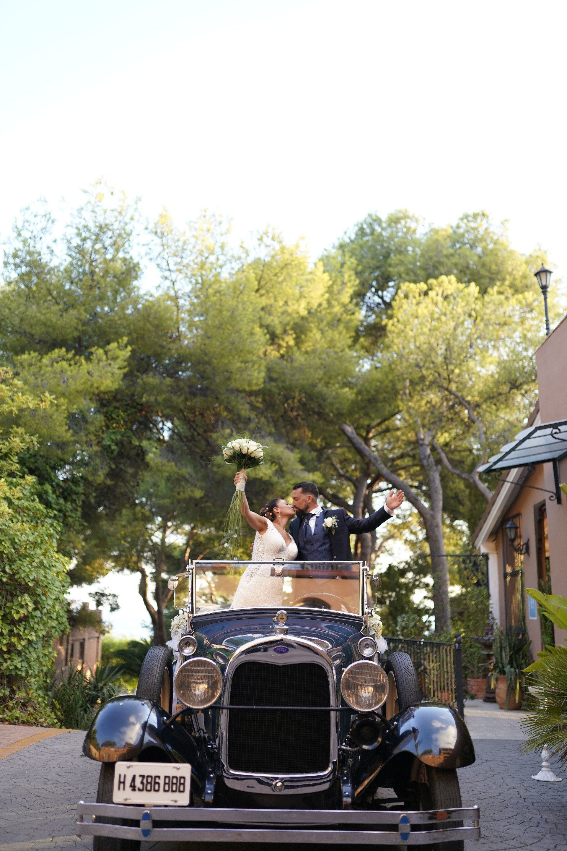 La pareja de novios se muestra cariño mutuo en el coche de boda, compartiendo un beso lleno de amor y felicidad en un momento emotivo y significativo