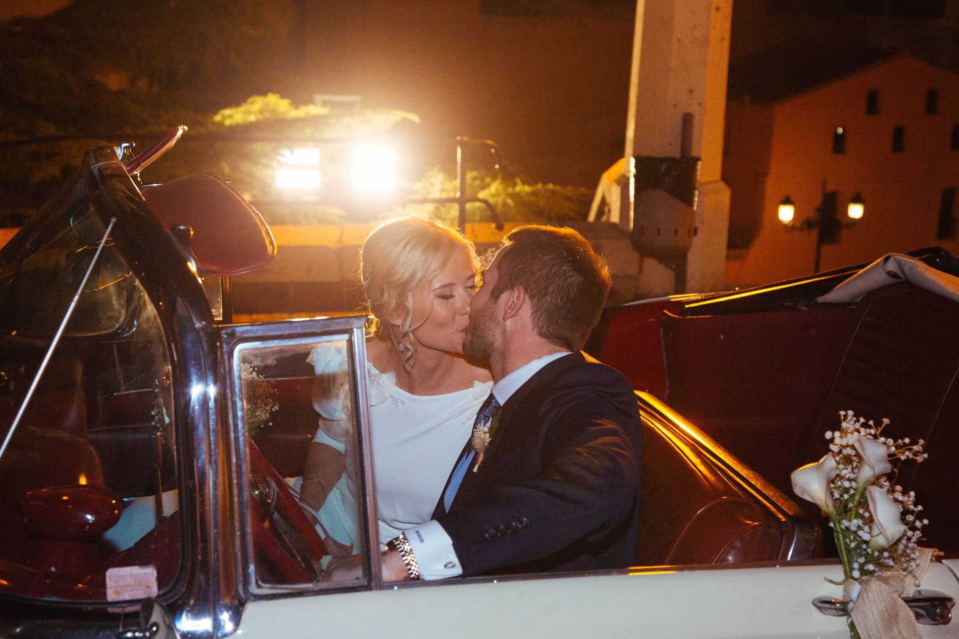 Fotógrafo de bodas en Valencia capturando a los novios besándose en el coche nupcial.