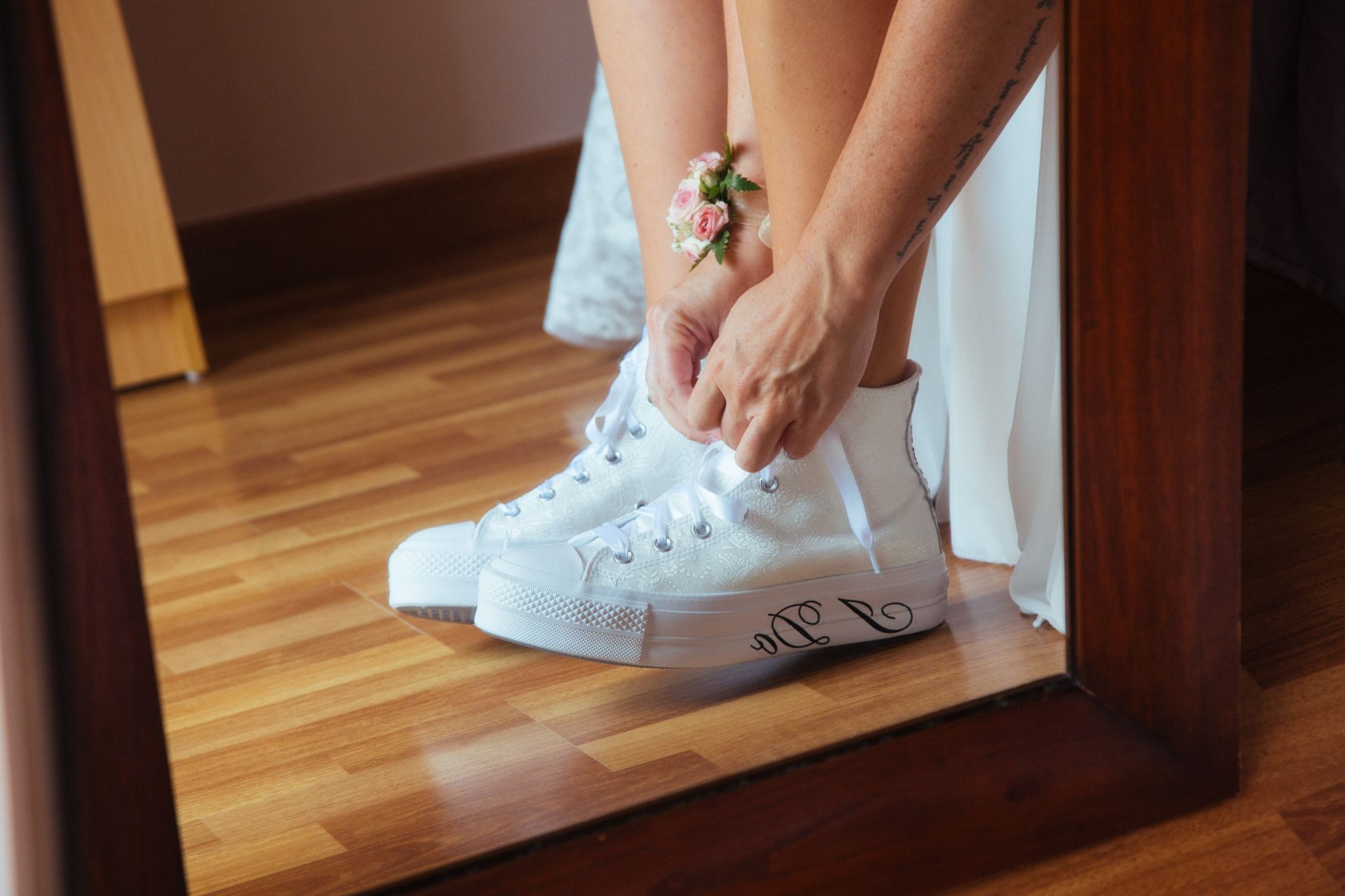 Fotógrafo de bodas en Valencia capturando el detalle de las zapatillas blancas Converse. Novia atándose los cordones el día de su enlace.