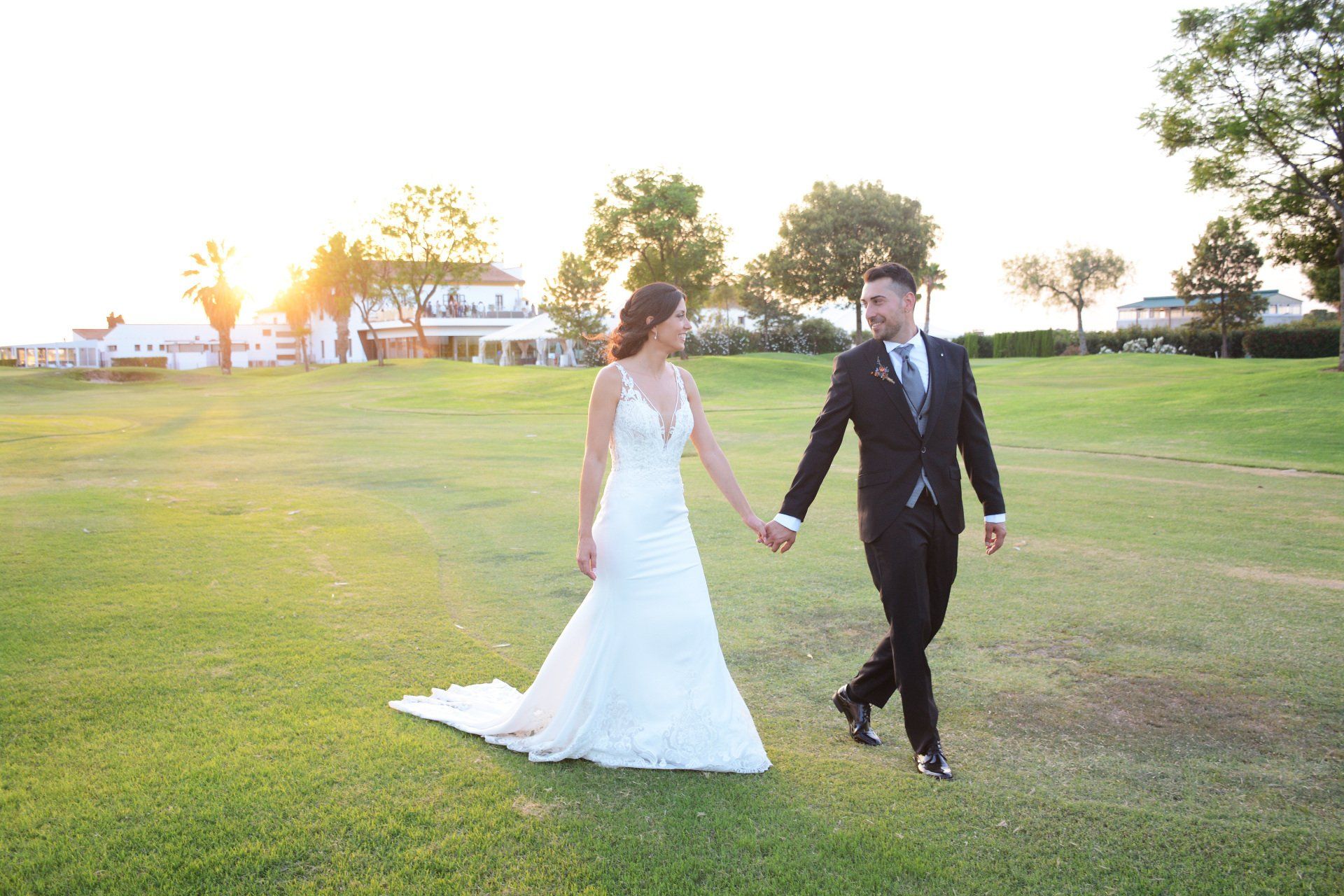 Foto de novios felices paseando en el club de golf de La Masía de las Estrellas en Catarroja, Valencia, disfrutando de un momento romántico en un entorno idílico