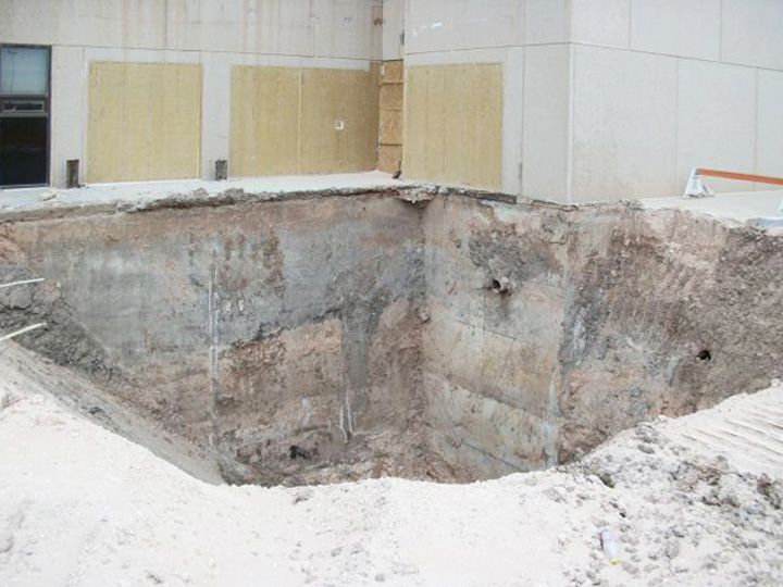 A large hole in the ground in front of a building