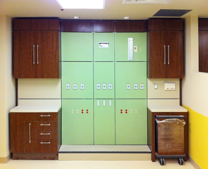 A hospital room with green cabinets and wooden cabinets