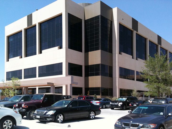 Several cars are parked in front of a large building