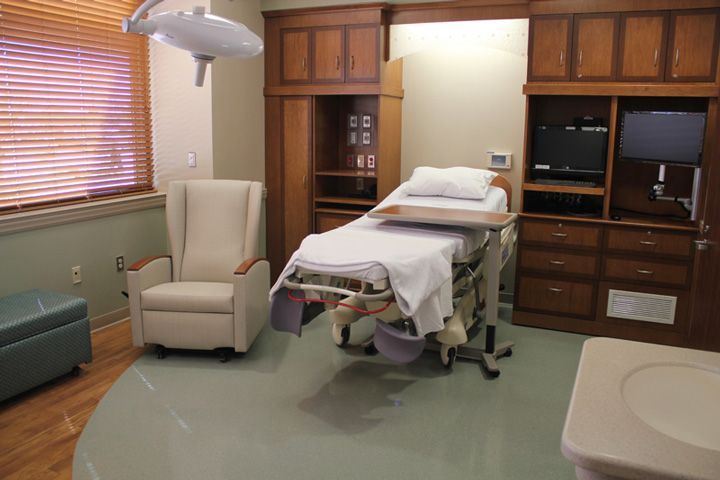 A hospital room with a bed a chair and a sink