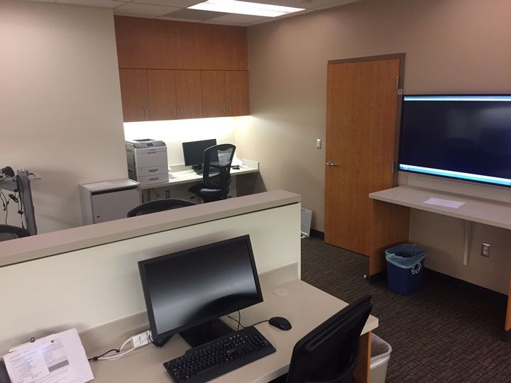 A computer is on a desk in a cubicle in an office