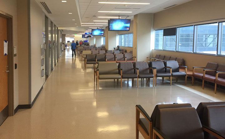 A long hallway with chairs and televisions in a hospital