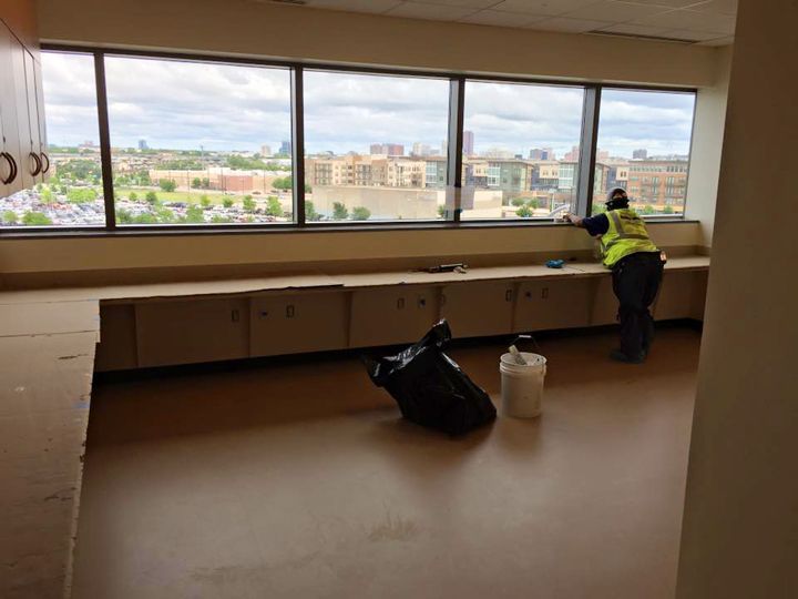A man in a yellow vest is cleaning a window