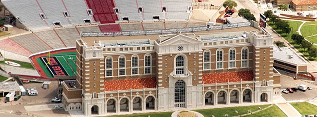 An aerial view of a large building with a stadium in the background.