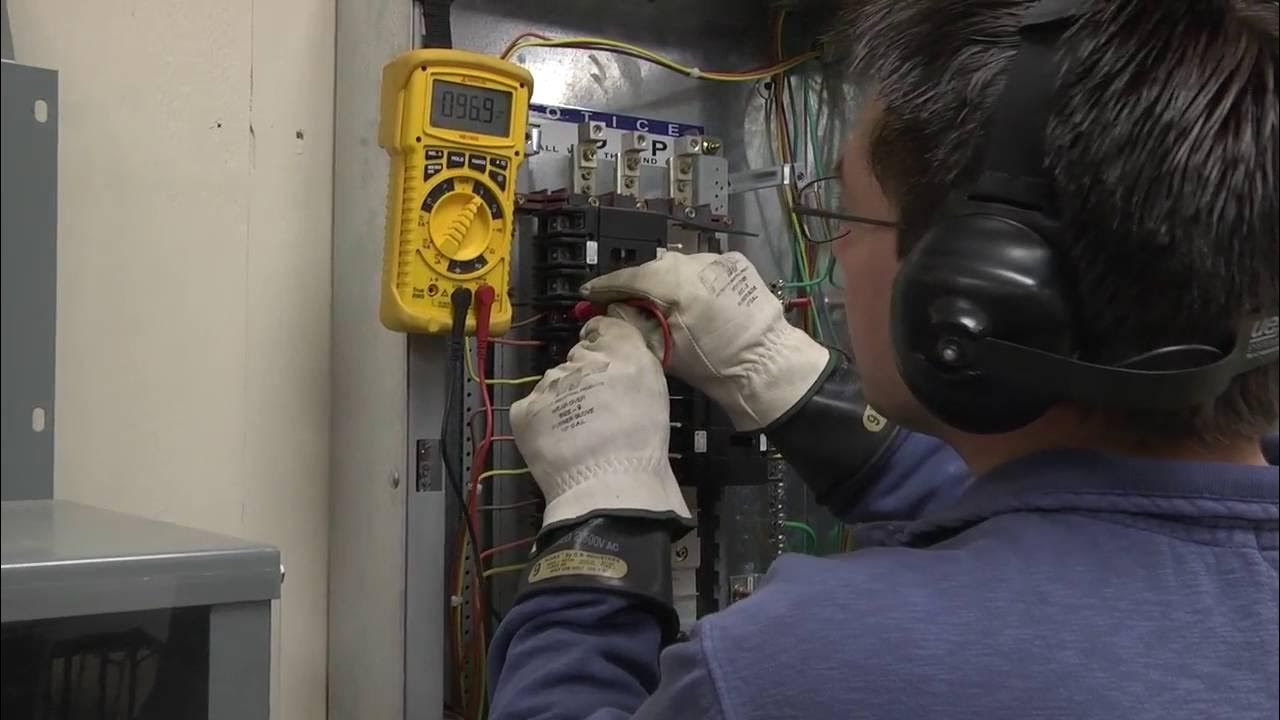 A man wearing headphones is working on an electrical box.