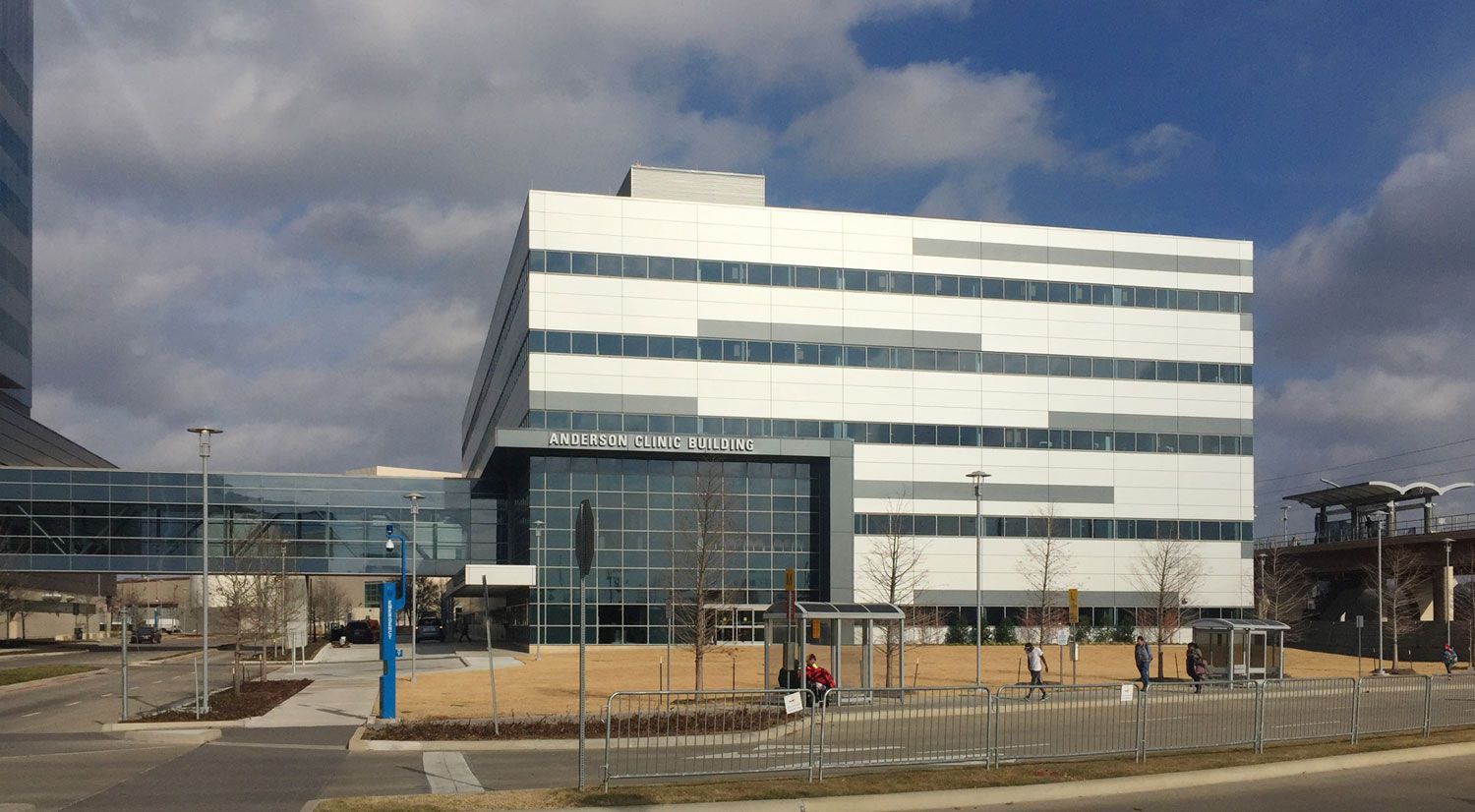 A large white building with a lot of windows is sitting next to a road.