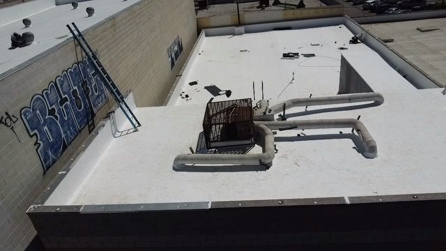 A white roof with pipes and graffiti on the side