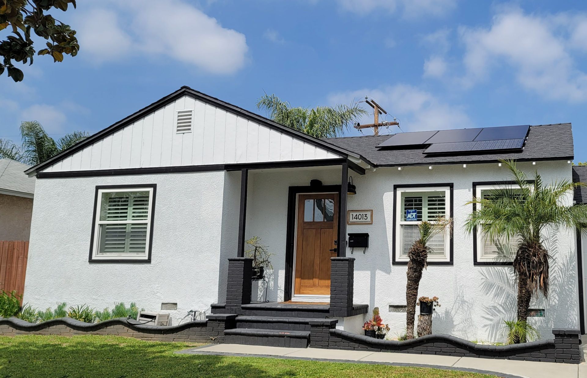 A white house with black trim and solar panels on the roof