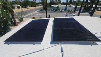Two solar panels are sitting on top of a white roof.
