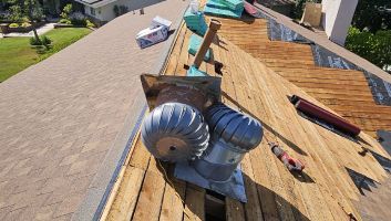 A roof with a wind turbine on it is being repaired.