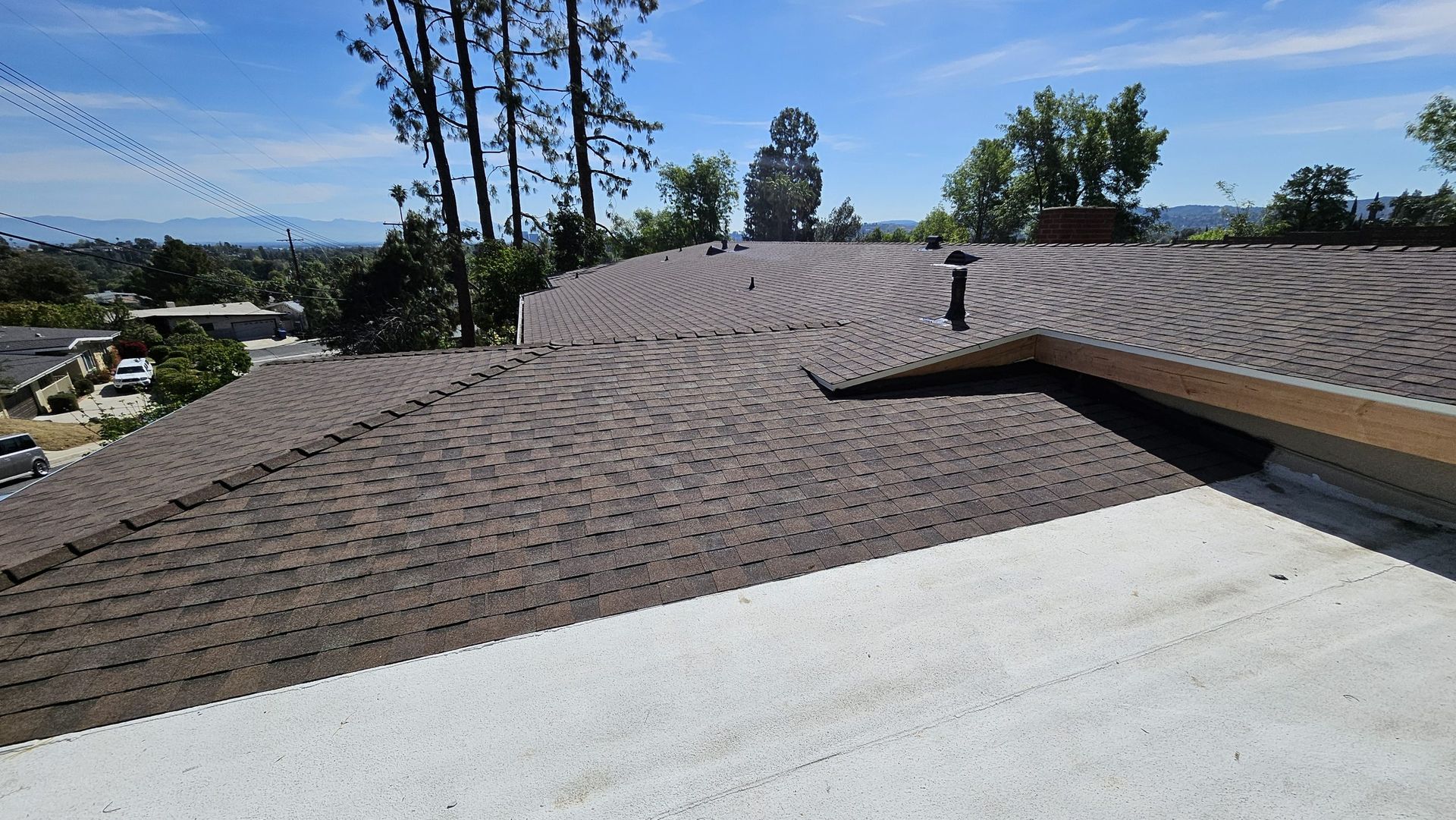 A roof with a chimney on it and trees in the background.