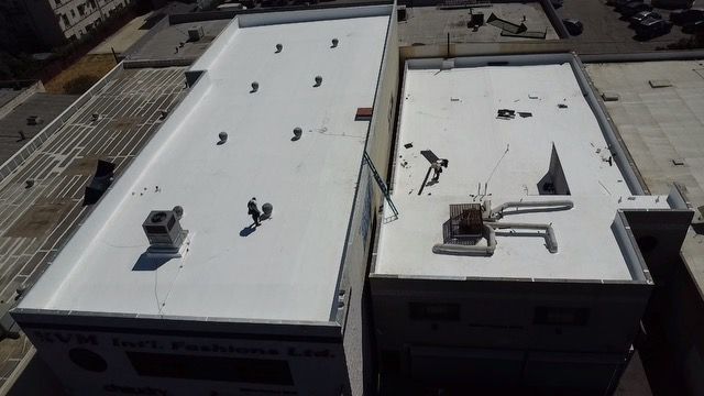 An aerial view of two buildings with white roofs.