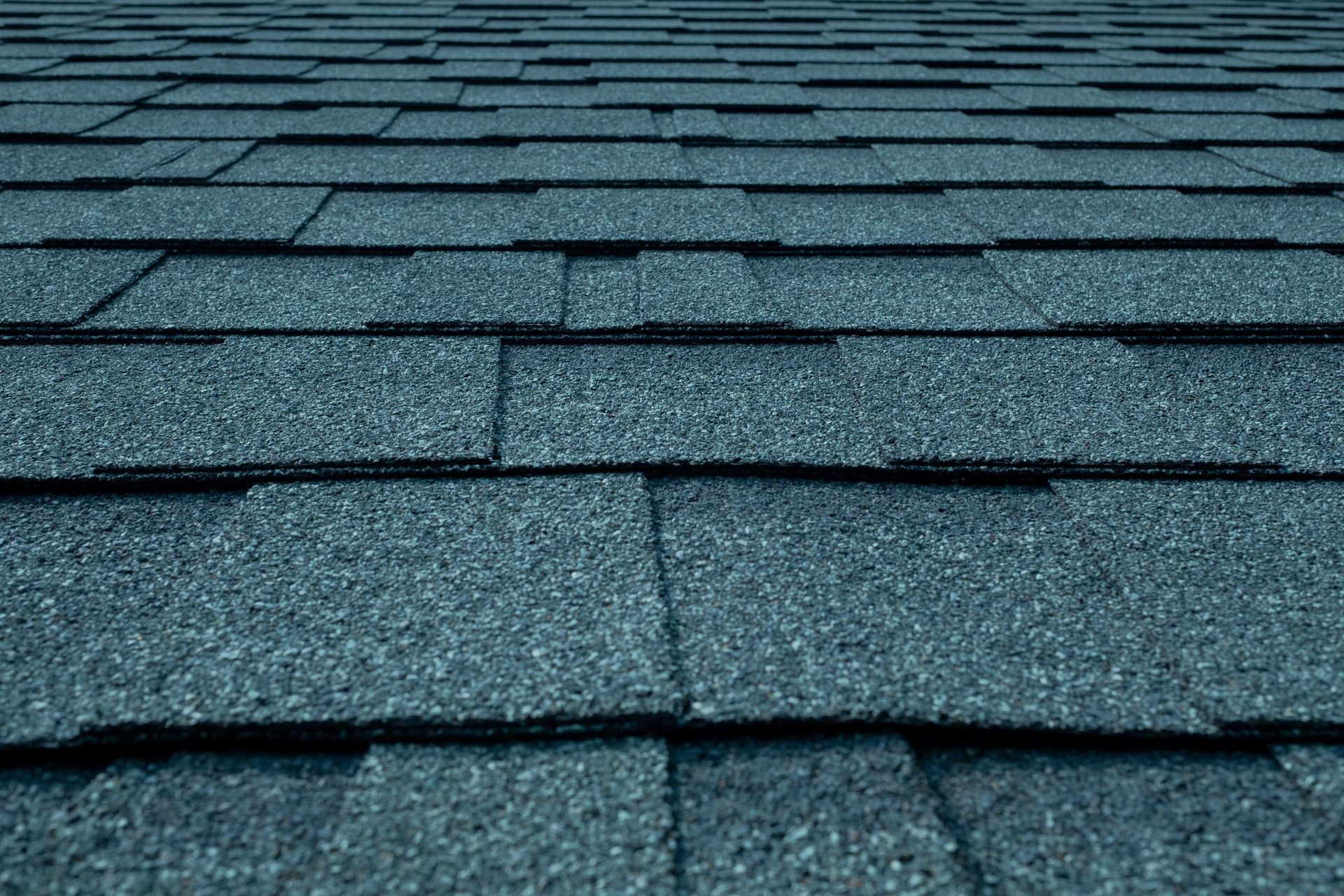 A close up of a roof with blue shingles.