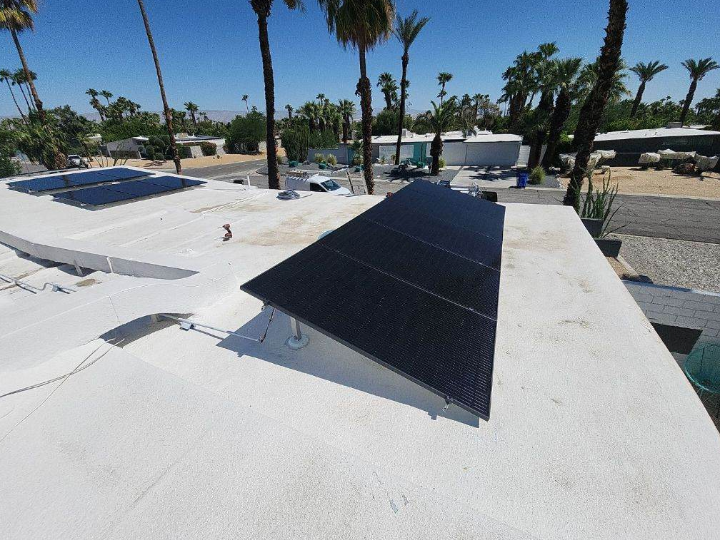 A solar panel is sitting on top of a white roof.
