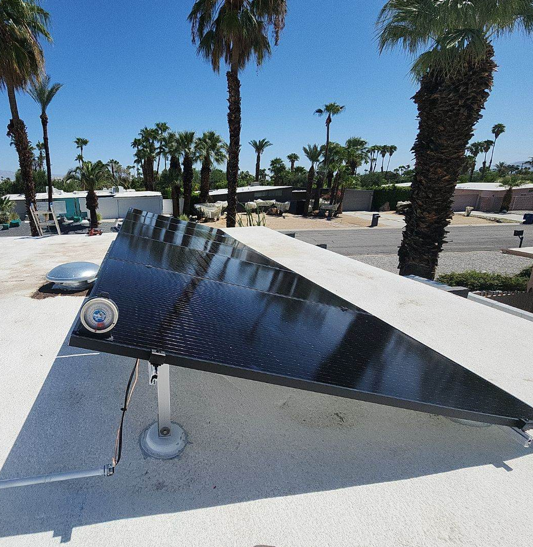 A solar panel on top of a roof with palm trees in the background