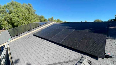 There are many solar panels on the roof of a house.