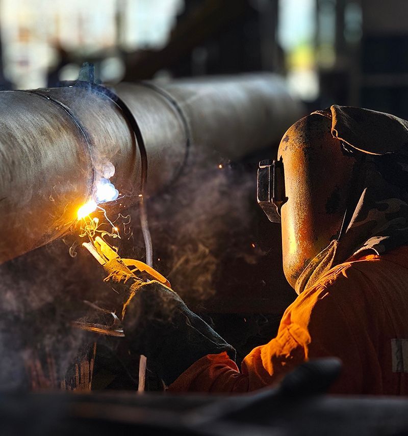 Worker Welding Metal Pipes