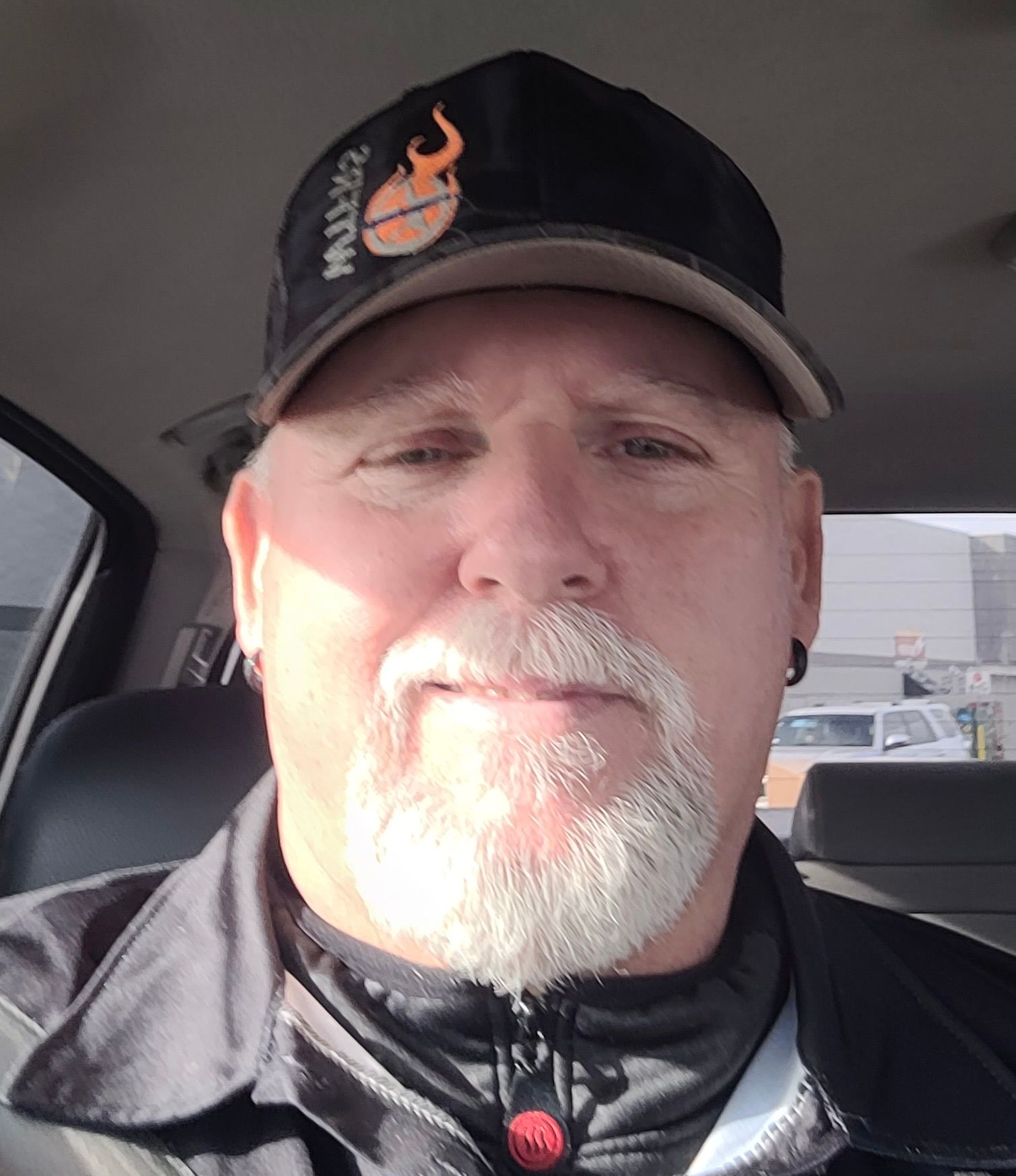 A woman wearing a black top and a white sweater is smiling for the camera.