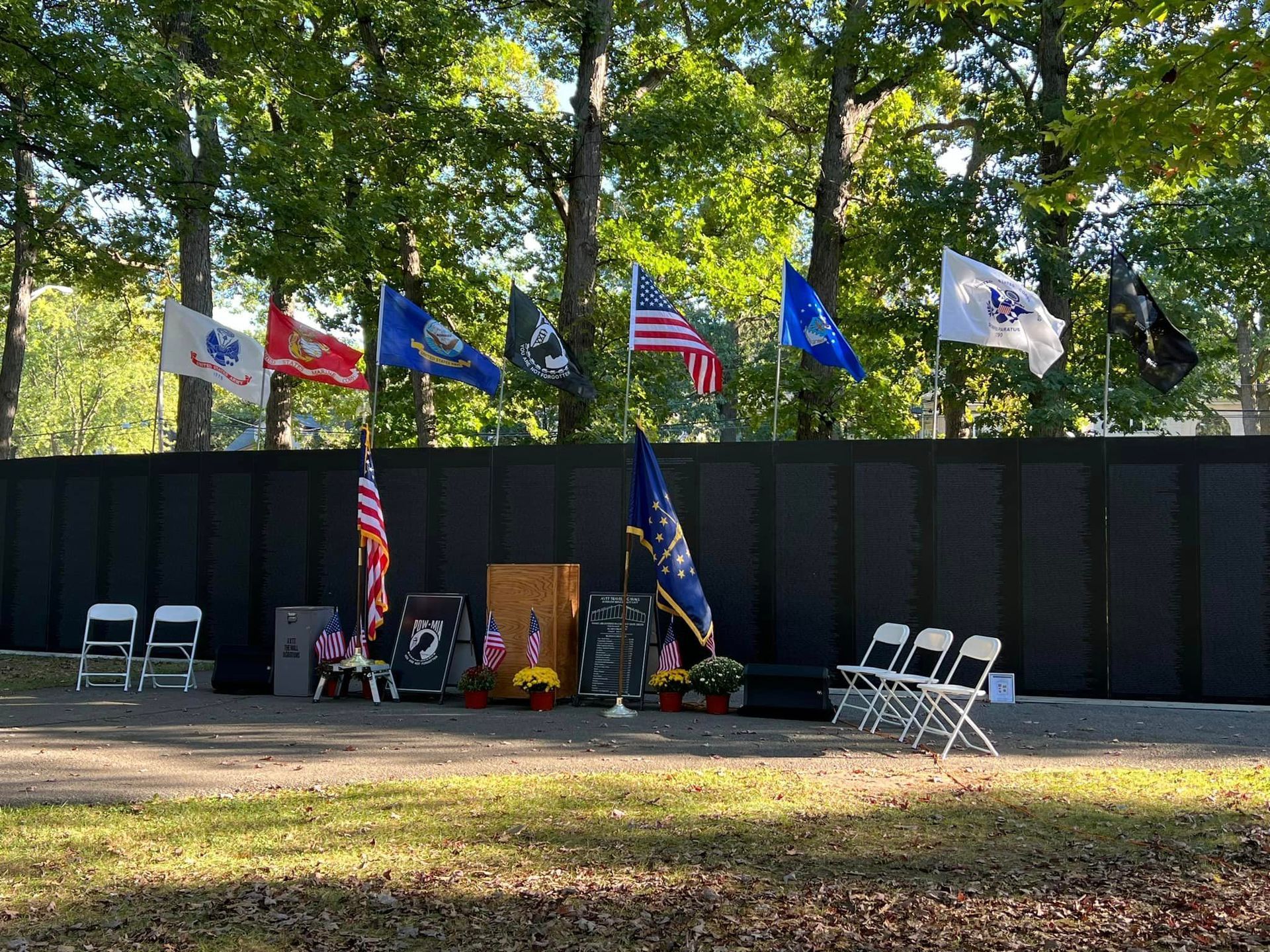 A black wall with flags and chairs in front of it.