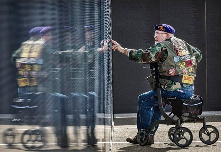 A man in a military uniform is sitting on a walker.